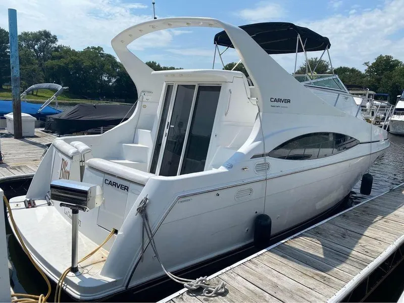 Slide: The Image of 1999 Carver 350 Mariner yacht docked at marina, featuring sleek white design and spacious deck. - 18