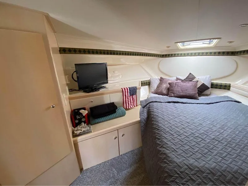 Slide: The Image of Cozy cabin interior of 1999 Carver 350 Mariner with bed, TV, and American flag decor. - 22