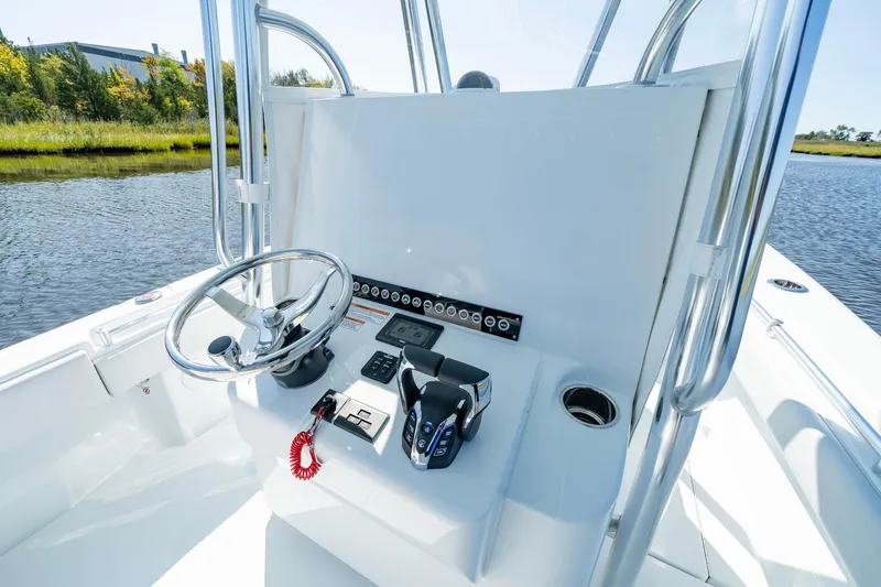 Slide: The Image of 2026 Contender 25T boat console with steering wheel and controls, on a calm waterway. - 4