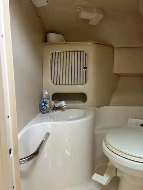 Slide: The Image of Compact bathroom in a 1998 Sea Ray 28 CC boat, featuring a sink and toilet. - 21