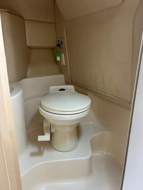 Slide: The Image of 1998 Sea Ray 28 CC boat bathroom with compact toilet and beige interior. - 22