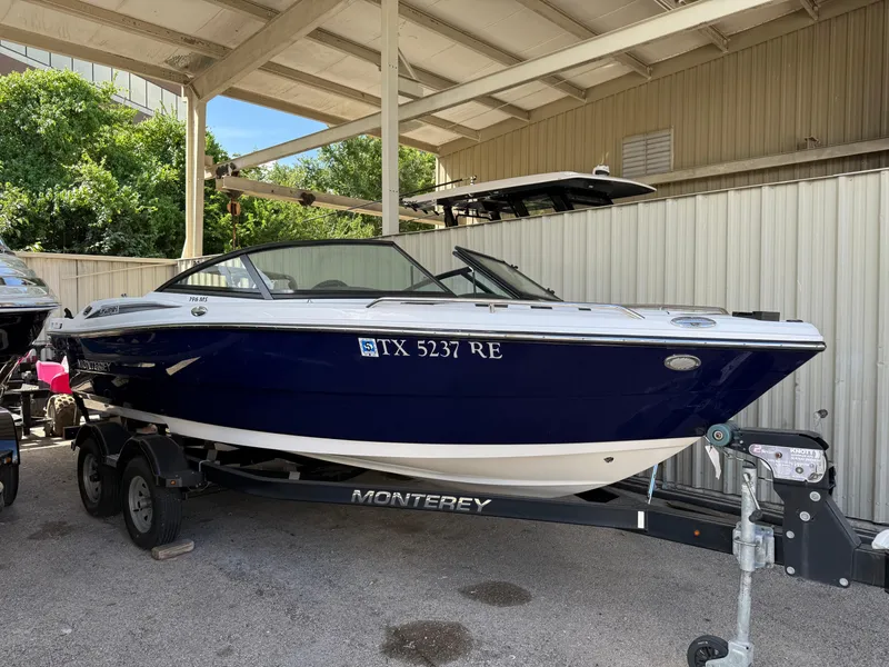 The Image of 2016 Monterey 196MS boat on trailer under shelter, blue and white exterior. - 1