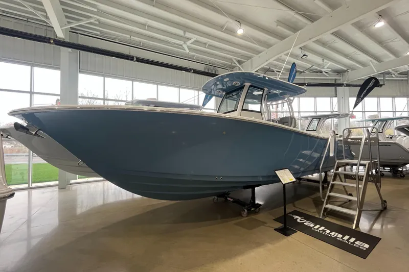 Slide: The Image of 2025 Sportsman Open 282 Center Console boat displayed indoors, blue hull, modern design. - 0