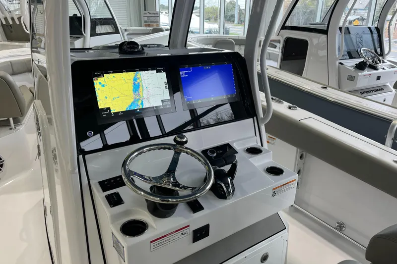 Slide: The Image of 2025 Sportsman Open 282 Center Console boat dashboard with navigation screens and steering wheel. - 2