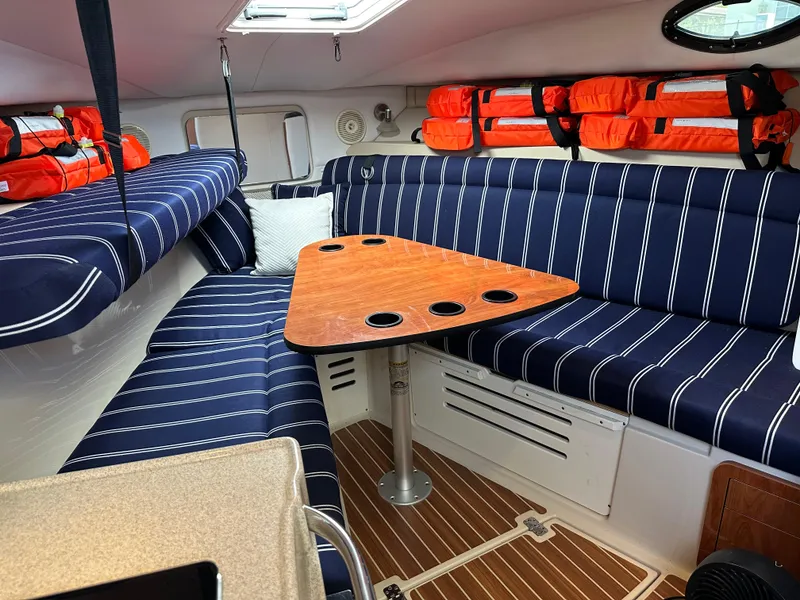 Slide: The Image of 2015 Wellcraft 290 Coastal cabin with striped seating, wooden table, and life jackets. - 10