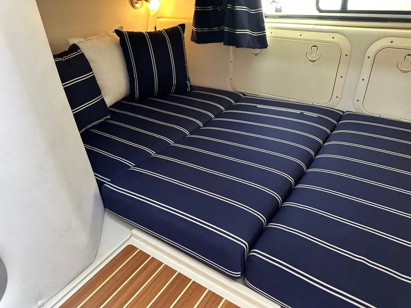 Slide: The Image of 2015 Wellcraft 290 Coastal cabin with striped navy cushions and wooden flooring. - 14