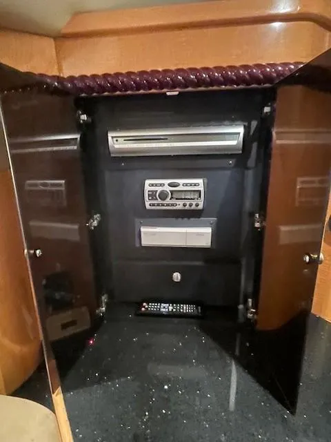 Slide: The Image of Entertainment system inside 2008 Larson Cabrio 330 Day Cruiser with open cabinet doors. - 13
