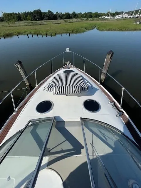 Slide: The Image of 2008 Larson Cabrio 330 Day Cruiser on calm water, featuring a striped sun pad. - 2