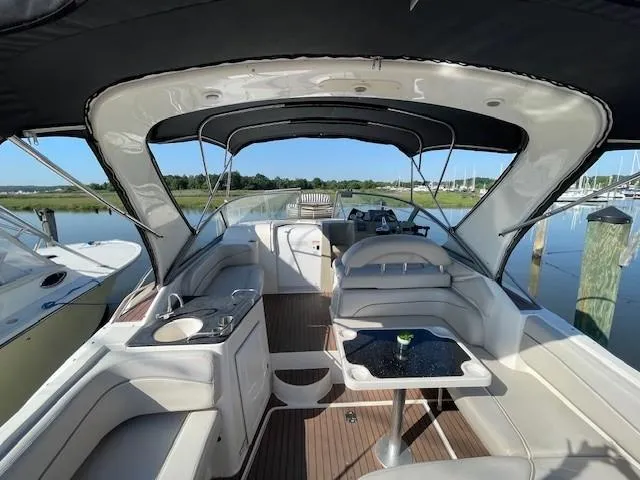 Slide: The Image of 2008 Larson Cabrio 330 Day Cruiser interior with seating, table, and helm, docked by calm waters. - 4