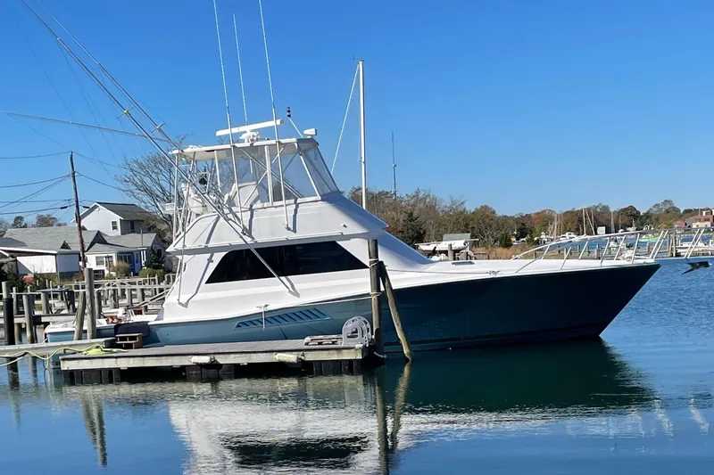 Slide: The Image of 1996 Viking 47 Convertible yacht docked in a serene marina setting. - 0
