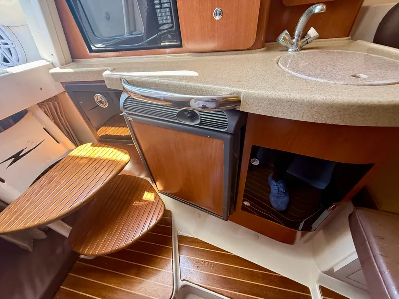 Slide: The Image of 2006 Hydra-Sports Vector VX interior with kitchenette, featuring wooden steps and compact appliances. - 25