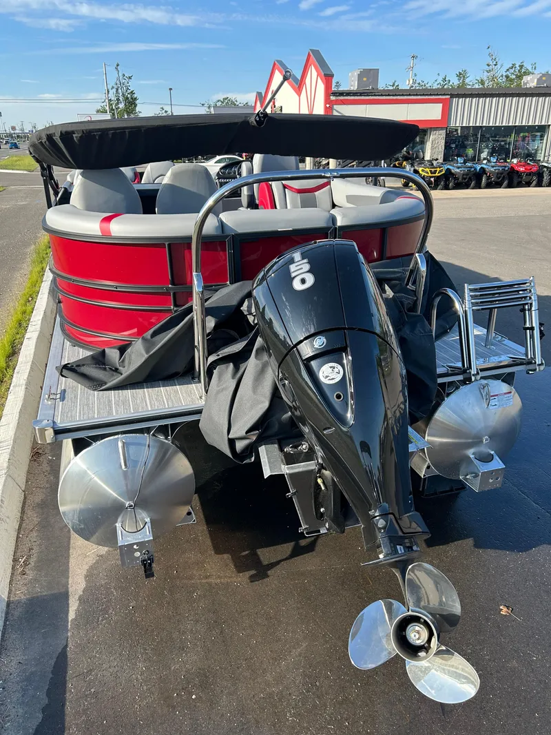 Slide: The Image of 2025 Trifecta 24ECS275 pontoon boat with outboard motor, parked outdoors. - 7