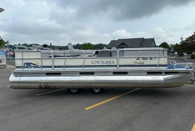 Slide: The Image of 1997 Suncruiser 22 pontoon boat parked on pavement under cloudy sky. - 2