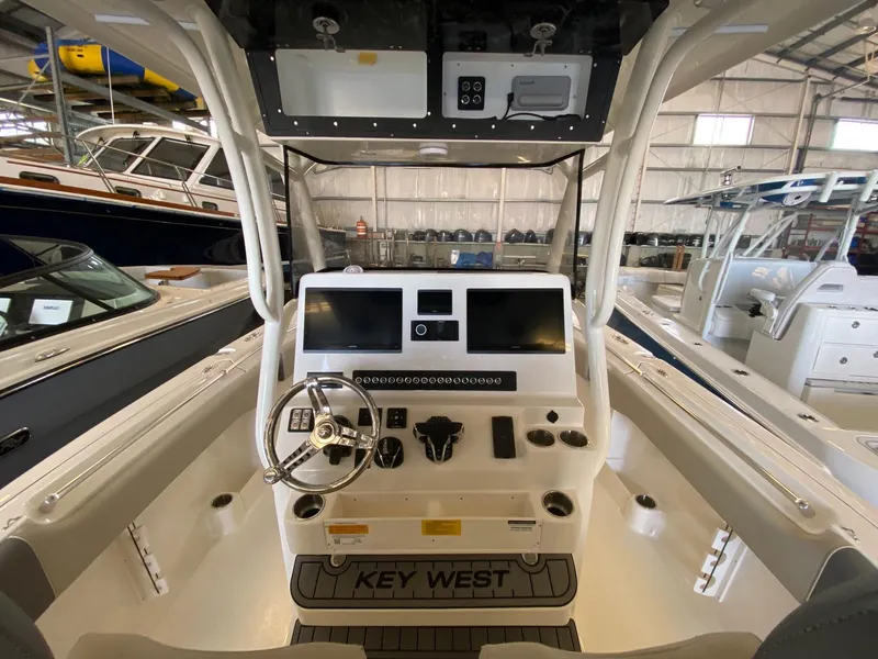 Slide: The Image of 2026 Key West 291 FS boat dashboard with dual screens and steering wheel in a showroom. - 4