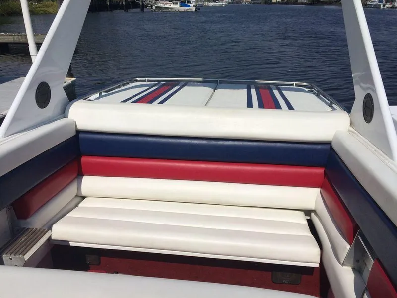Slide: The Image of 1988 Fountain 12 Meter boat interior with red, white, and blue seating by the water. - 12