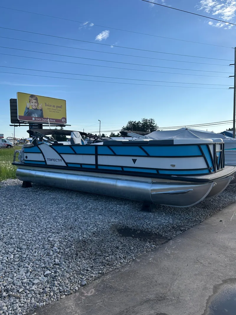 The Image of 2024 Trifecta 25C SS pontoon boat on gravel lot under clear sky. - 0