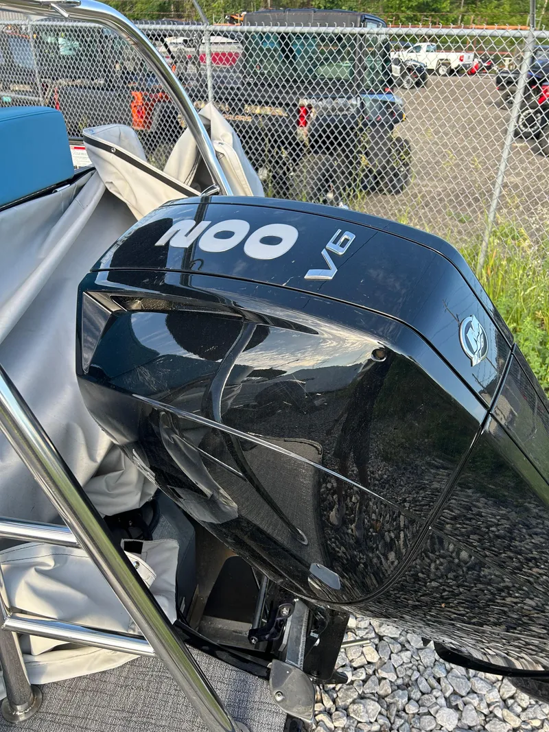 Slide: The Image of 2024 Trifecta 25C SS boat with a 200 V6 outboard motor, parked near a chain-link fence. - 7