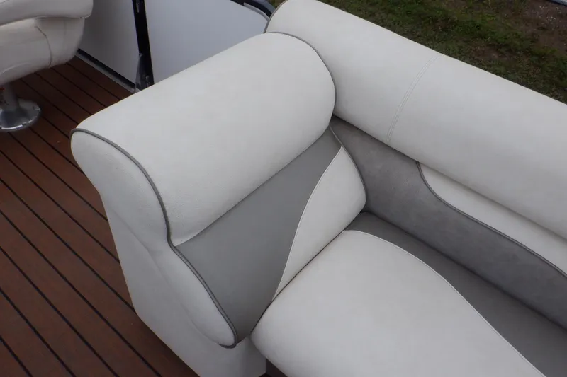 Slide: The Image of 2019 Premier 220 SunSation boat seating with white and gray upholstery on wooden deck. - 25