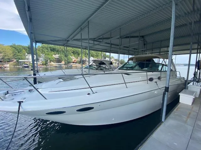 Slide: The Image of 2001 Sea Ray 380 Sundancer docked under a covered marina, surrounded by calm waters. - 2