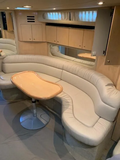 Slide: The Image of Interior of 2001 Sea Ray 380 Sundancer with curved seating and wooden table. - 39