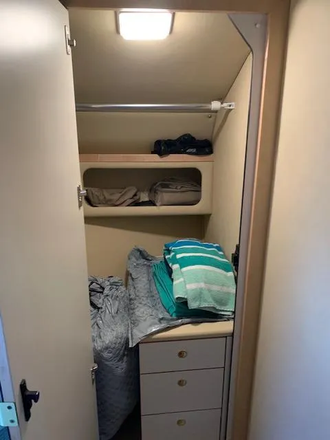 Slide: The Image of Closet interior on 2001 Sea Ray 380 Sundancer with folded clothes and storage shelves. - 44