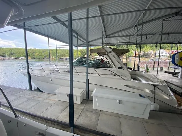 Slide: The Image of 2001 Sea Ray 380 Sundancer docked under a covered marina with scenic lake view. - 6