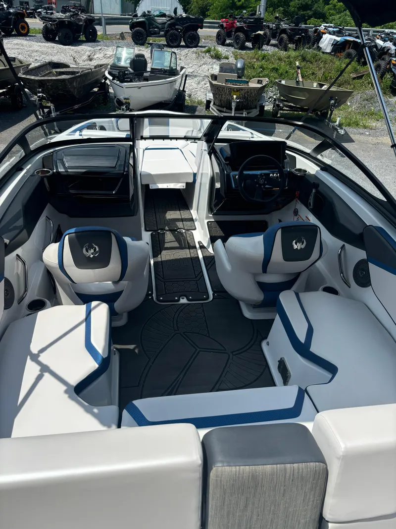 Slide: The Image of 2025 Scarab 195 H.O. boat interior with modern seating and dashboard, parked outdoors. - 3