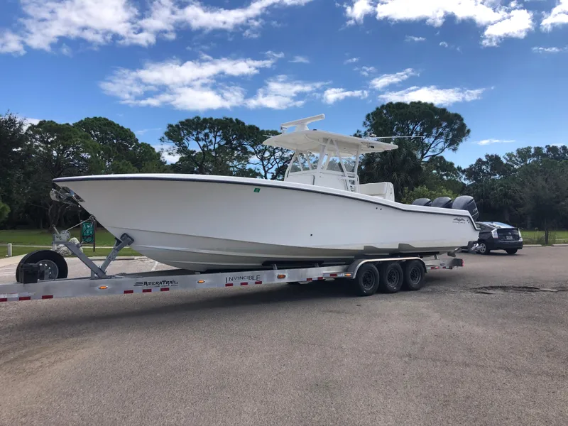 The Image of 2011 Invincible 36 CC boat on trailer, parked outdoors under a blue sky. - 0