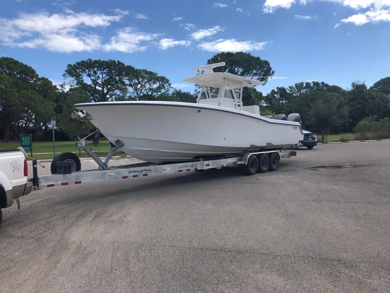 Slide: The Image of 2011 Invincible 36 CC boat on trailer in parking lot, clear sky background. - 1