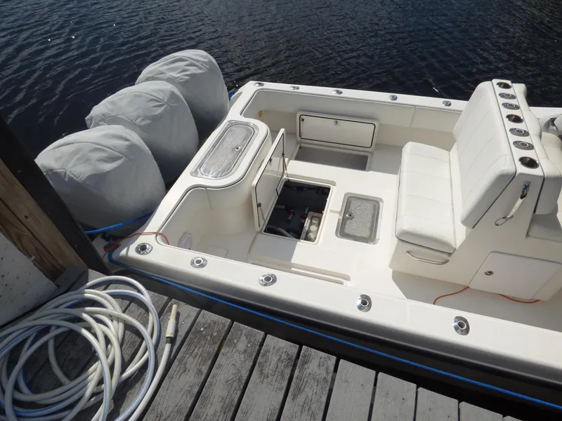 Slide: The Image of 2011 Invincible 36 CC boat docked, featuring white seating and storage compartments. - 13