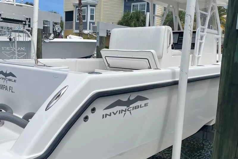 Slide: The Image of 2011 Invincible 36 CC boat docked, featuring sleek white design and spacious seating. - 16