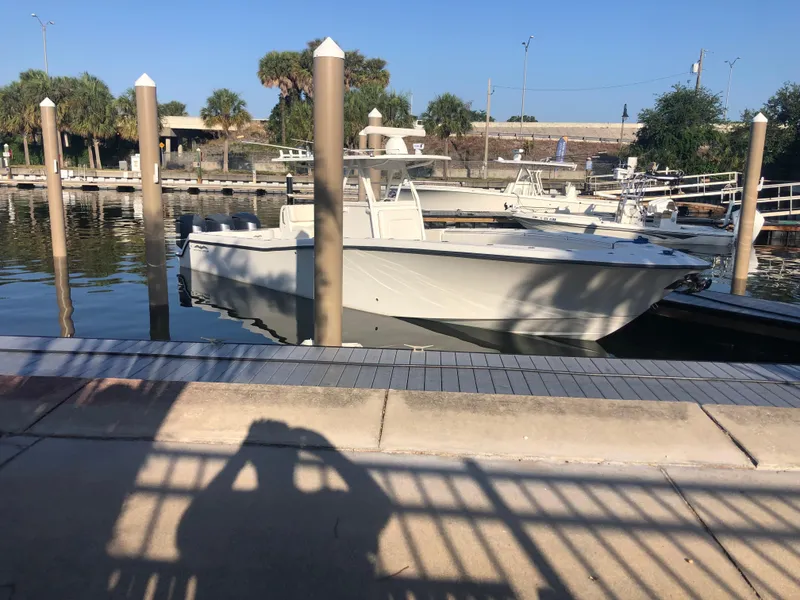 Slide: The Image of 2011 Invincible 36 CC boat docked at marina, surrounded by calm water and palm trees. - 2