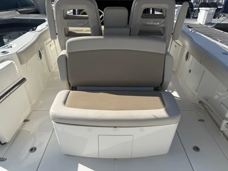 Slide: The Image of 2021 Boston Whaler 330 Outrage boat seating area with cushioned bench and storage. - 13