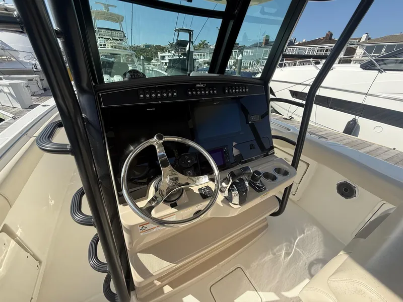 Slide: The Image of 2021 Boston Whaler 330 Outrage helm with steering wheel and navigation controls. - 18