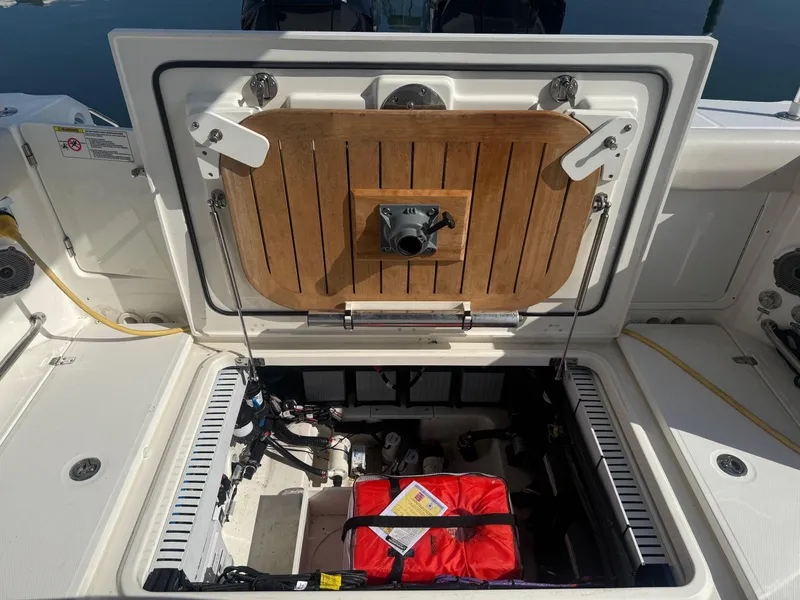 Slide: The Image of Boston Whaler 330 Outrage 2021 boat storage compartment with open hatch and visible equipment. - 21