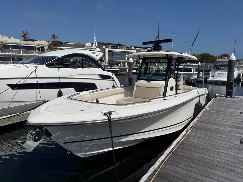 Slide: The Image of 2021 Boston Whaler 330 Outrage docked at a marina under a clear blue sky. - 6