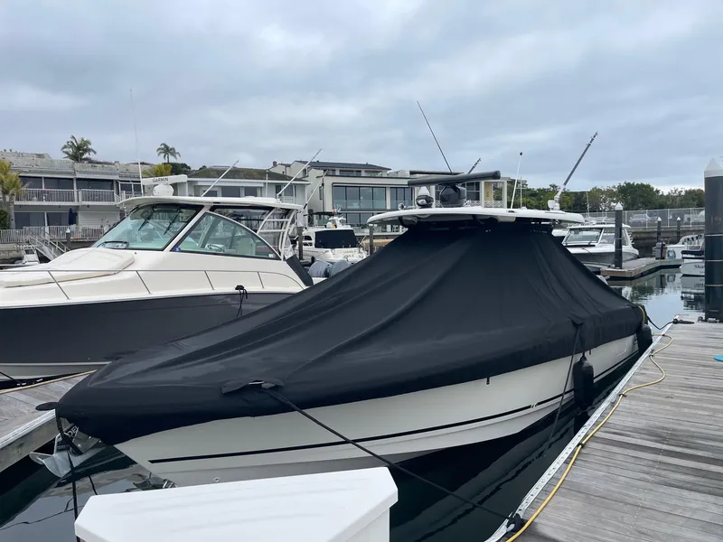 Slide: The Image of 2021 Boston Whaler 330 Outrage covered at marina dock, overcast sky. - 8