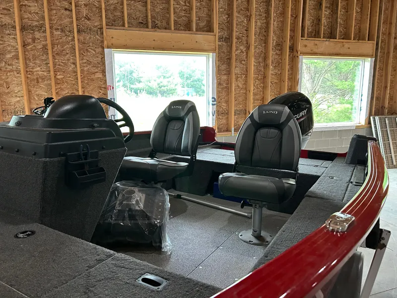 Slide: The Image of 2023 Lund 1650 Rebel XL Sport boat interior with two seats in a wooden garage. - 2