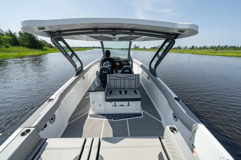 Slide: The Image of 2026 Monterey Elite 30 OB boat cruising on a serene river under a clear sky. - 11