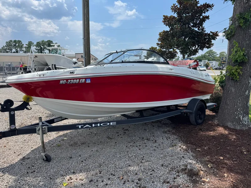 The Image of 2020 Tahoe 550TS boat in red and white on a trailer, parked outdoors. - 1