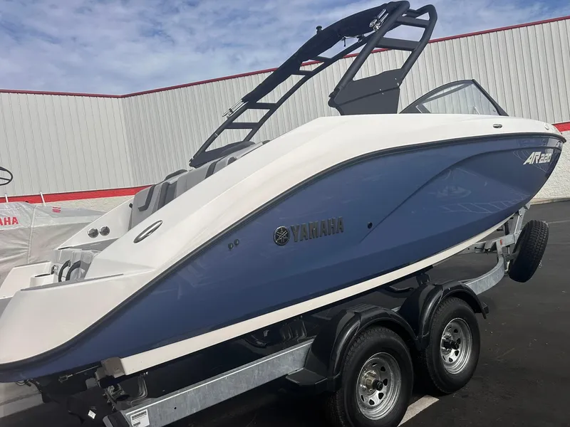 Slide: The Image of 2025 Yamaha AR220 boat on trailer, blue and white design, parked outdoors. - 27