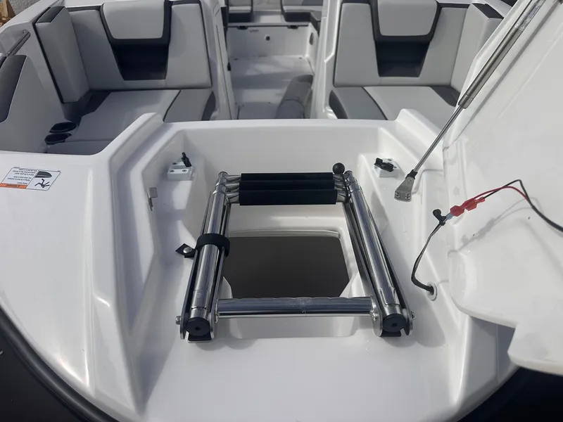 Slide: The Image of 2025 Yamaha Boats AR220 interior with seating and ladder compartment. - 29