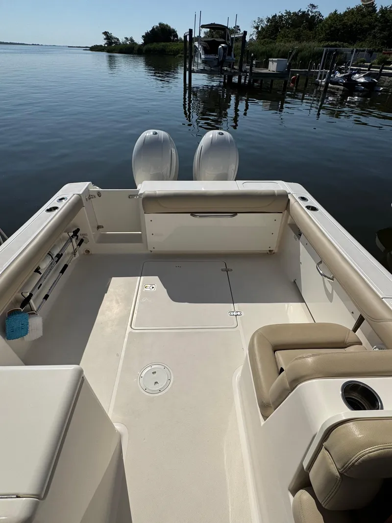Slide: The Image of 2016 Pursuit DC 265 Dual Console boat interior with seating, docked by calm water. - 18