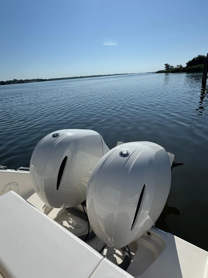 Slide: The Image of 2016 Pursuit DC 265 Dual Console boat with twin engines on calm water. - 19