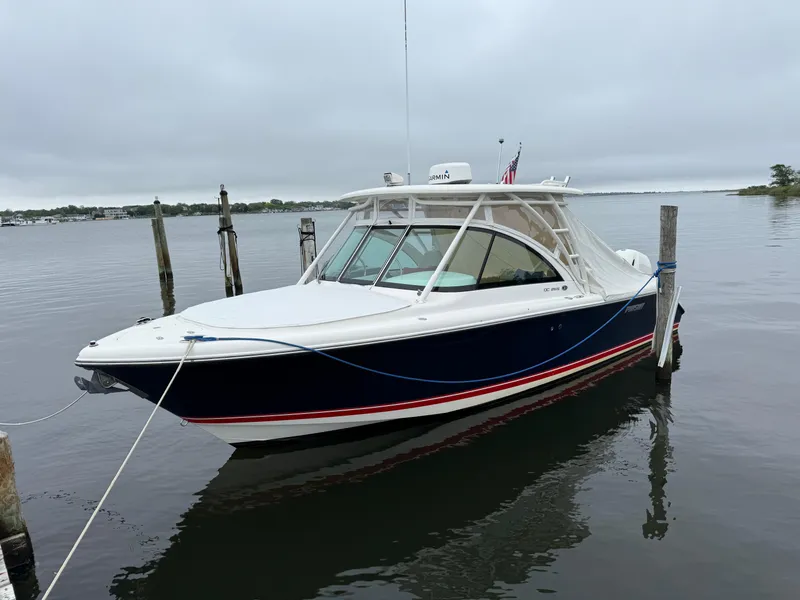 Slide: The Image of 2016 Pursuit DC 265 Dual Console boat docked on calm water. - 2