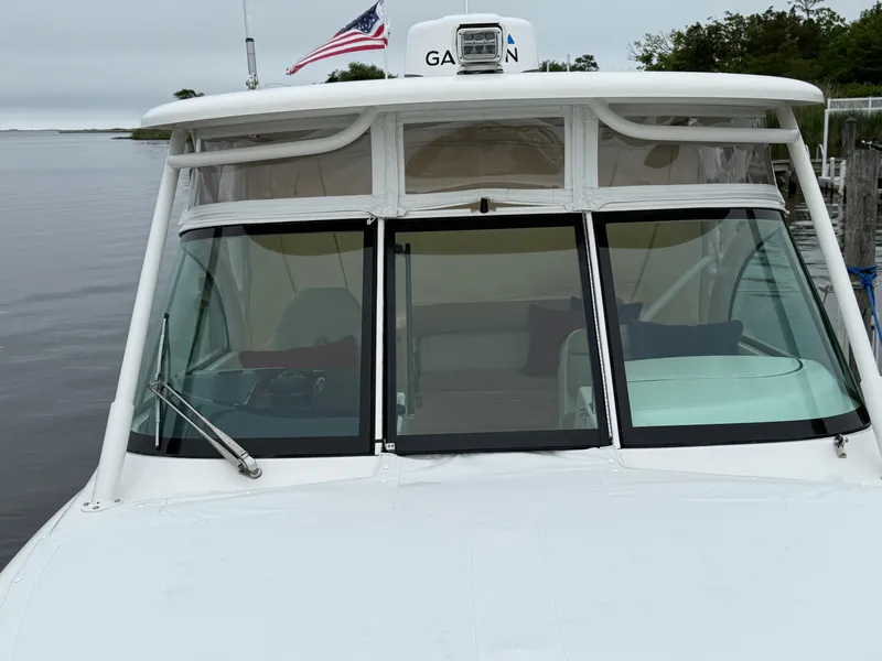 Slide: The Image of 2016 Pursuit DC 265 Dual Console boat with American flag, docked by calm waters. - 4