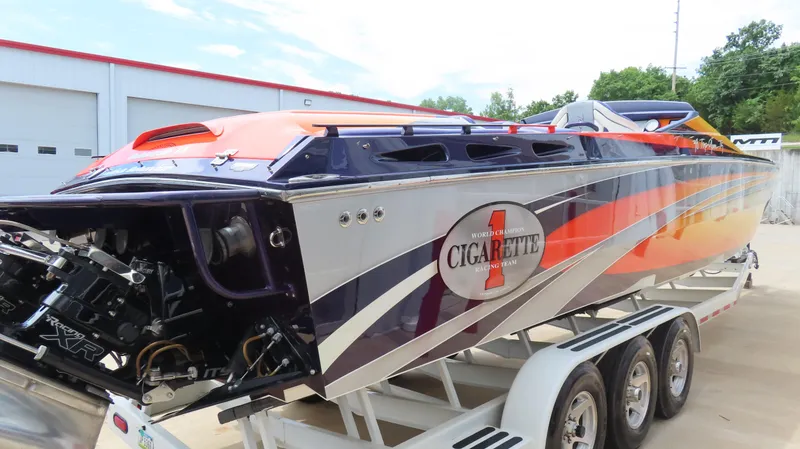 Slide: The Image of 2005 Cigarette 38 Top Gun speedboat with vibrant orange and blue design on a trailer. - 13