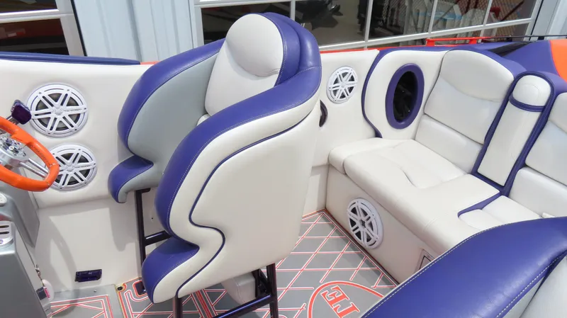 Slide: The Image of 2005 Cigarette 38 Top Gun interior with blue and white seating, orange steering wheel, and speakers. - 22