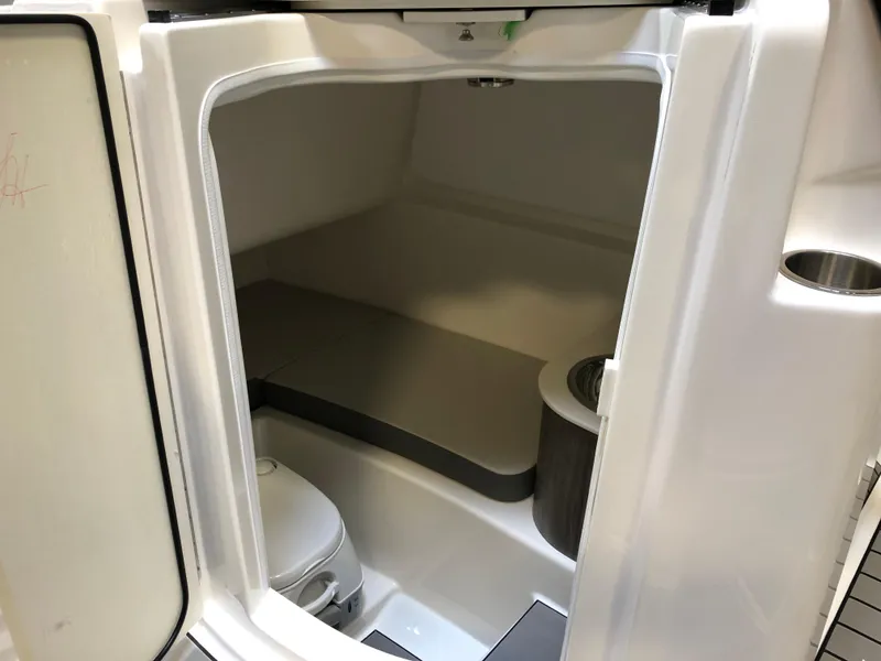 Slide: The Image of Interior cabin of 2025 Sea Ray SDX 270 boat, featuring compact toilet and seating area. - 10