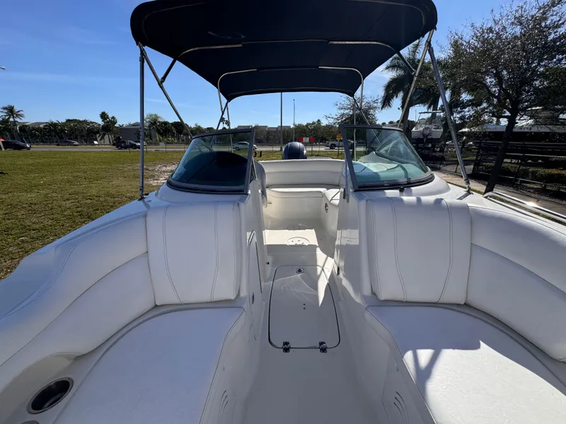 Slide: The Image of 2017 Hurricane 2000SD boat interior with white seating and canopy, parked outdoors. - 33